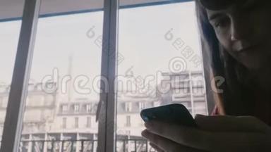 迷人的高加索女人使用智能手机社交应用程序坐在美丽的巴黎公寓窗口，<strong>火车经过</strong>。